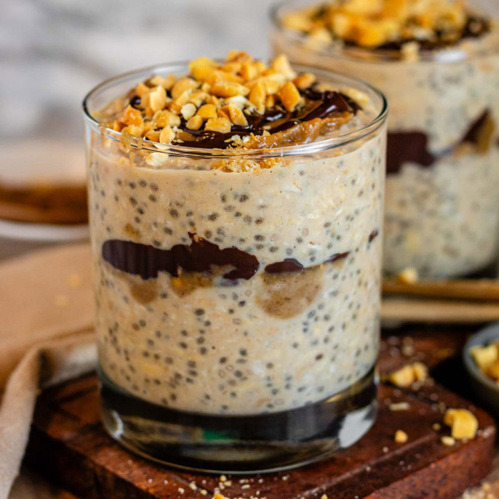 Oats in a glass topped with caramel, chocolate, and peanuts.