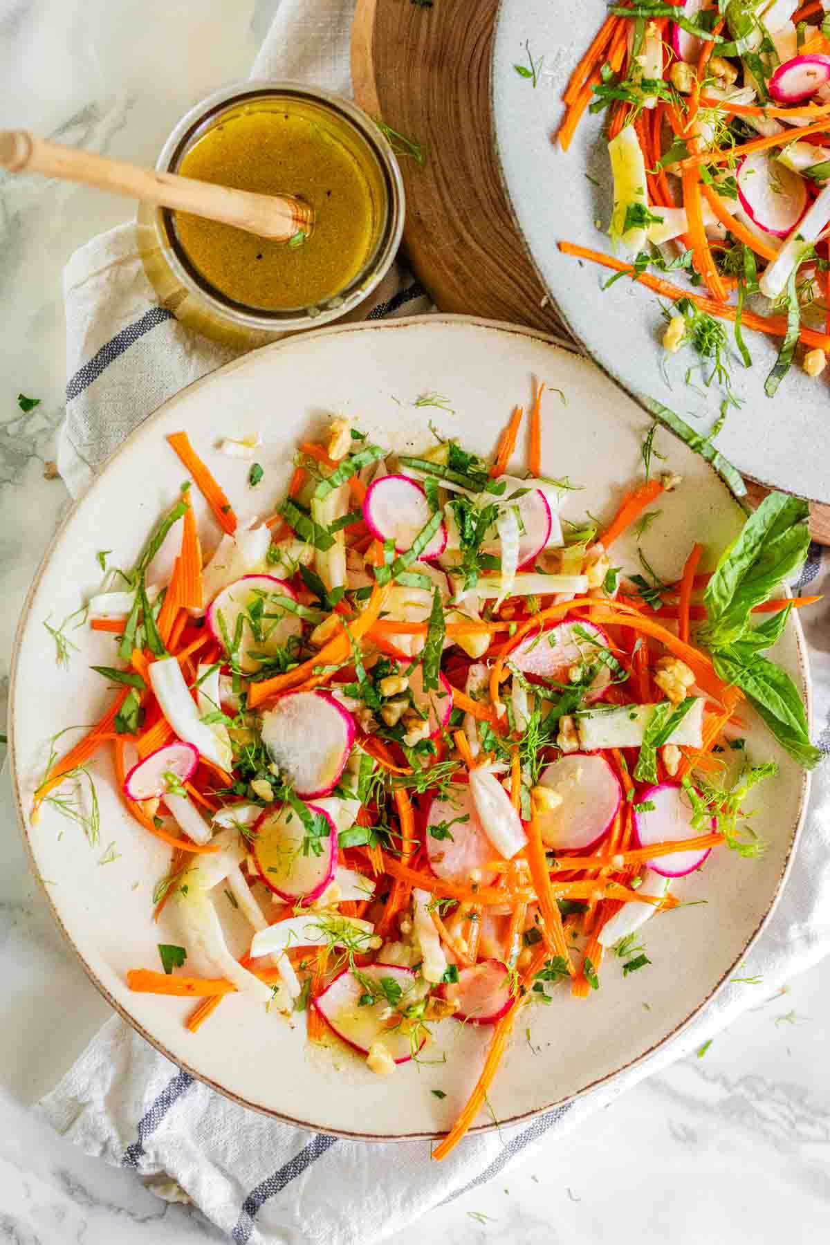 Sliced vegetables on plates topped with fresh herbs and a fork.